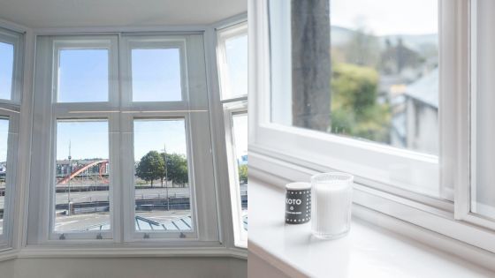 Large bay windows with a city view and a bright window sill featuring decorative candles.