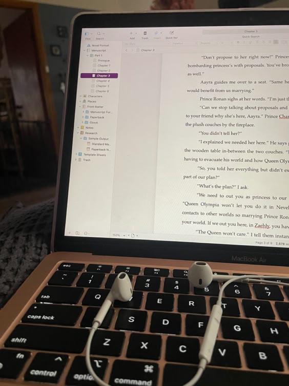 Open laptop with earphones on keyboard, displaying a document in a writing app.