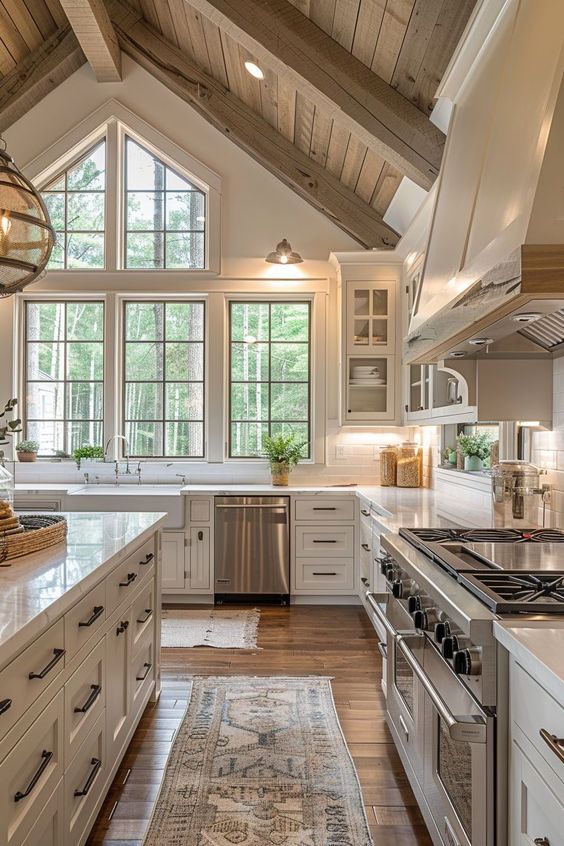 Spacious rustic kitchen with vaulted ceilings, large windows, white cabinetry, and stainless-steel appliances.