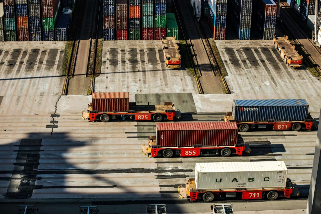 Automated trucks transporting shipping containers at a busy industrial port terminal.