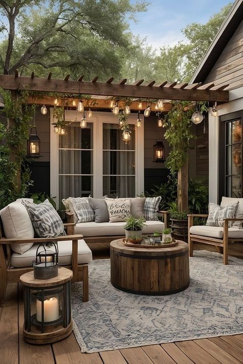 Cozy outdoor patio with pergola, string lights, and comfy seating set on a wooden deck, surrounded by greenery.