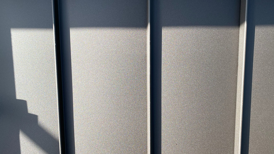 Close-up of textured steel panels with shadows, showing industrial design and modern architectural features.