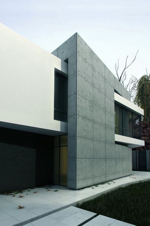 Modern minimalist concrete house exterior with large windows and clean lines, surrounded by greenery.