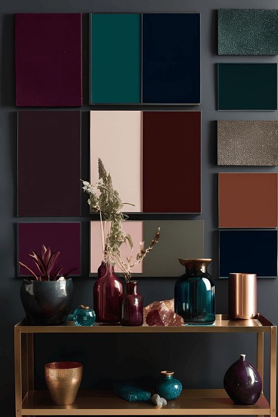 Decorative wall art and vases on a shelf showcasing rich, deep colors in a modern interior design setting.