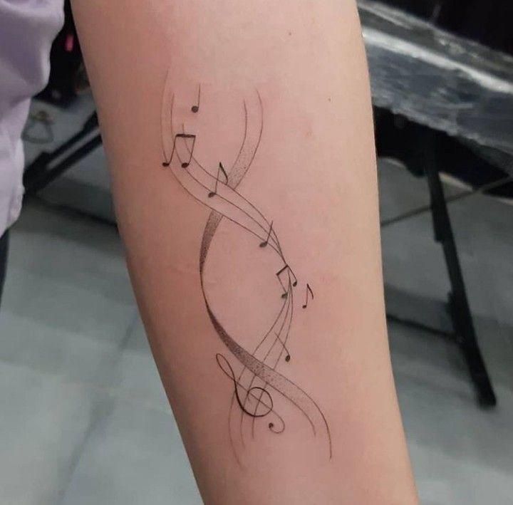 Minimalist tattoo of a DNA strand with musical notes on a forearm.