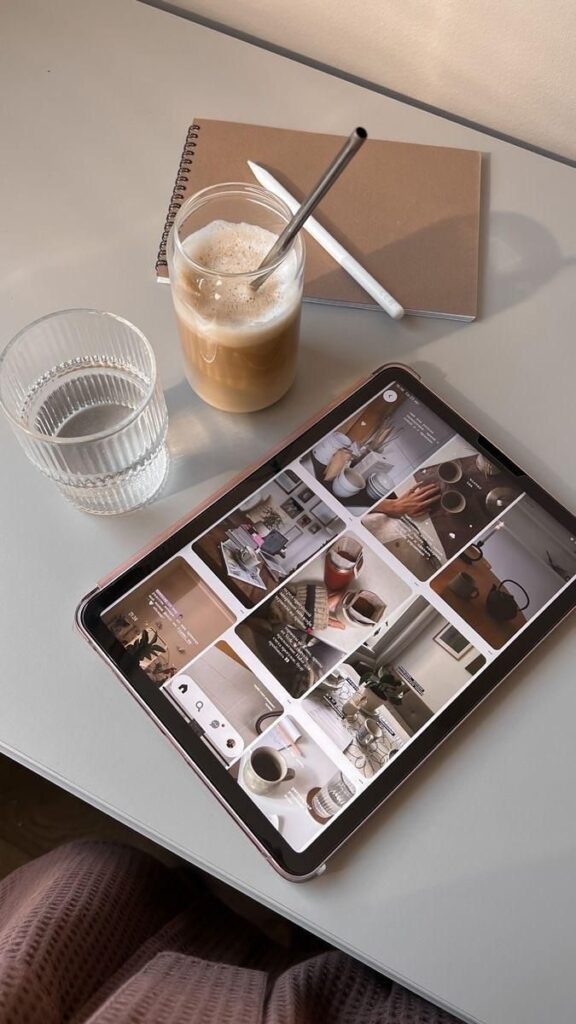 Tablet on desk with iced coffee, notebook, and a glass of water for a cozy workspace vibe.