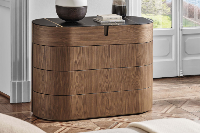 Modern wooden dresser with curved edges and decorative items on top, placed in a bright, stylish room.