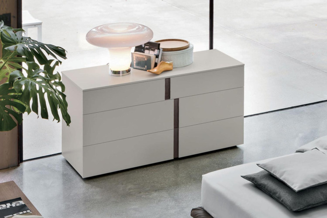 Modern white dresser with sleek design, elegant lamp, houseplant, and décor items in a minimalist living space.