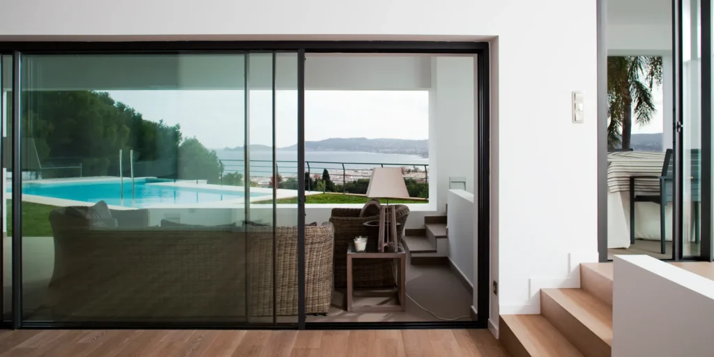 Modern living room with sliding glass doors overlooking pool and ocean view.