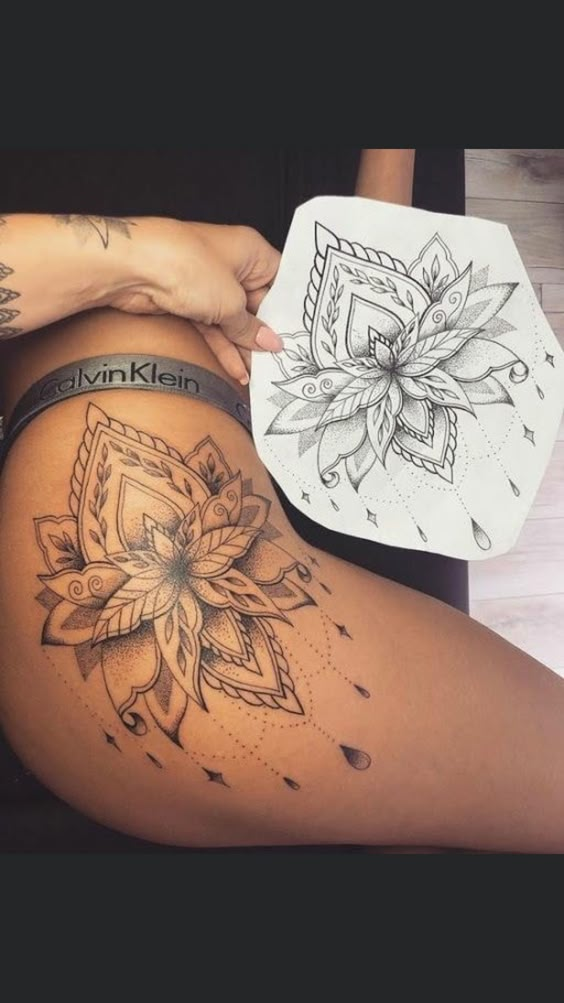 Intricate mandala thigh tattoo with matching design sketch on paper, showcasing detailed floral and geometric patterns.