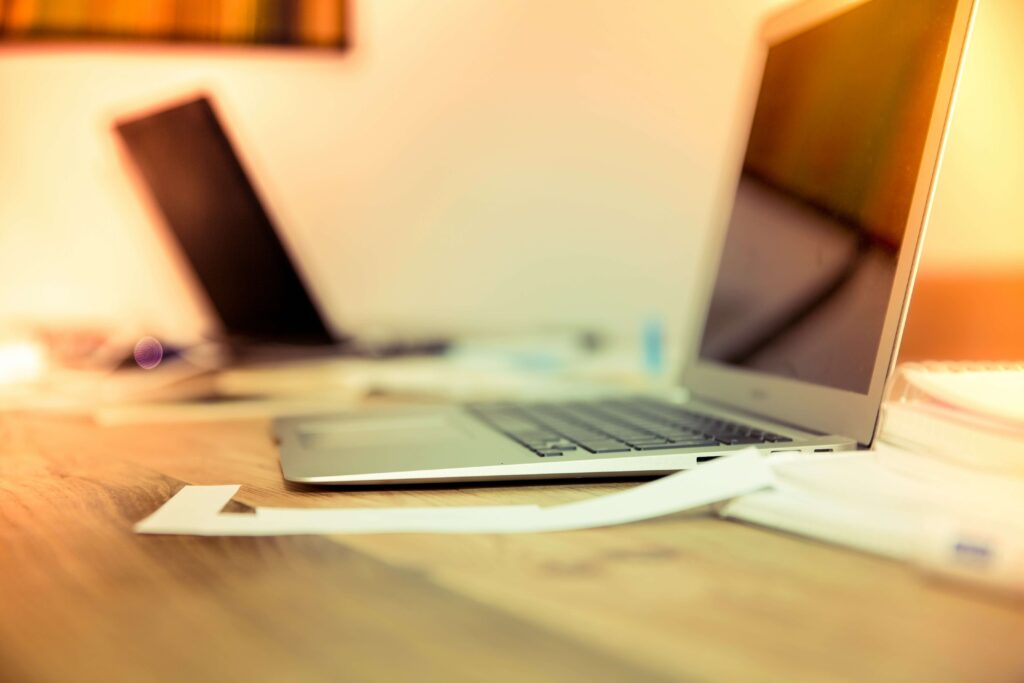 Open laptop on a wooden desk with scattered papers, creating a productive workspace ambiance.