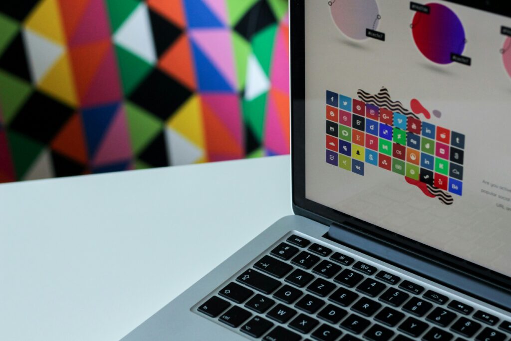 Laptop displaying colorful social media icons with geometric background.