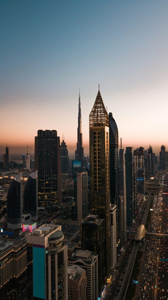 Dubai skyline at sunset, featuring tall skyscrapers and bustling city life along the main highway.