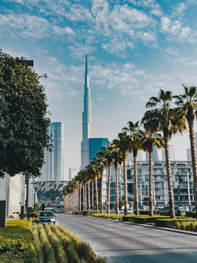 Burj Khalifa with palm-lined street in Dubai, blue sky background.