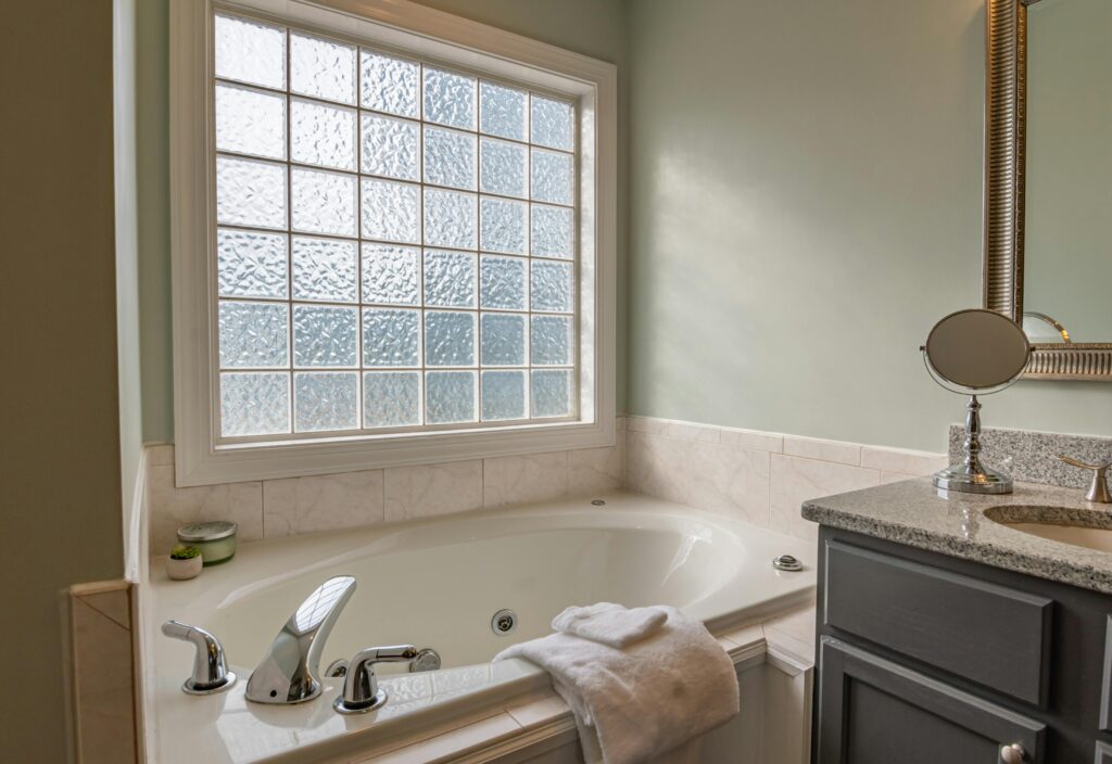 Luxurious bathroom with elegant bathtub, marble tiles, and a large frosted glass window for natural light.