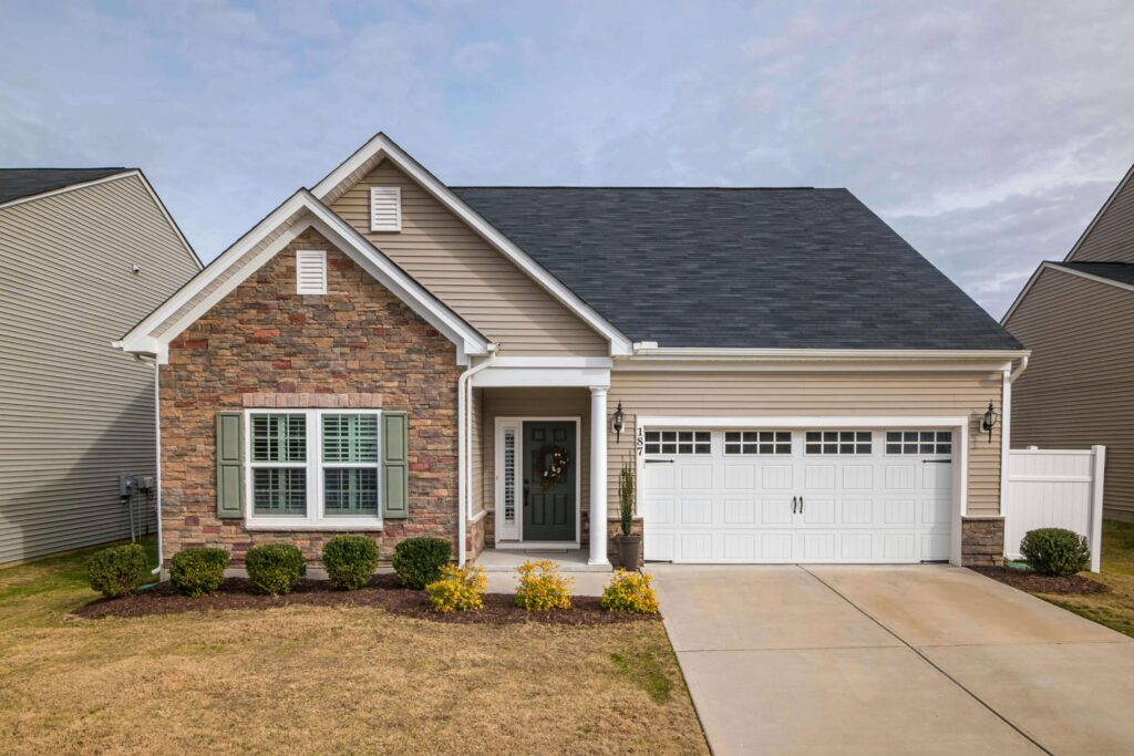 Suburban home with brick frontage, white garage door, and manicured lawn under a cloudy sky.