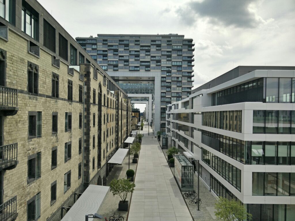 Modern and historic buildings flanking a street under cloudy sky, illustrating urban architectural contrast.