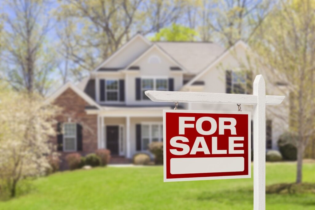 House for sale with a green lawn and white picket sign in the front yard. Perfect opportunity for home buyers.