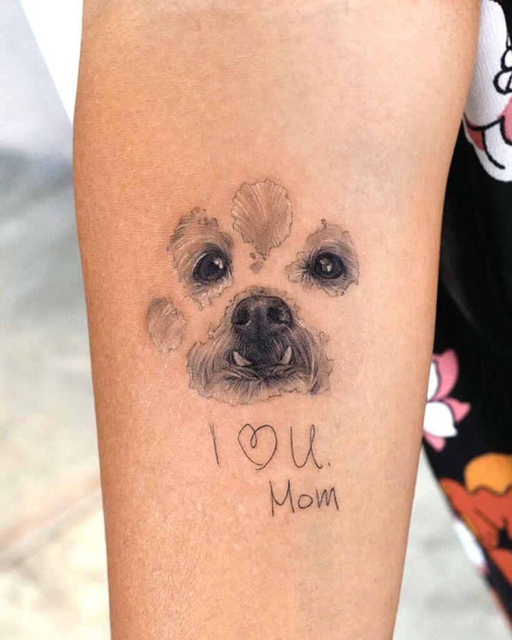 Tattoo of a dog's face with the text I ♥ U Mom on an arm, expressing love and appreciation.