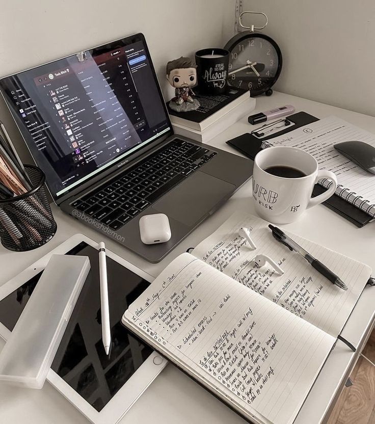 A cozy workspace with a laptop, notebooks, coffee mug, and stationery, ideal for productivity and focus.