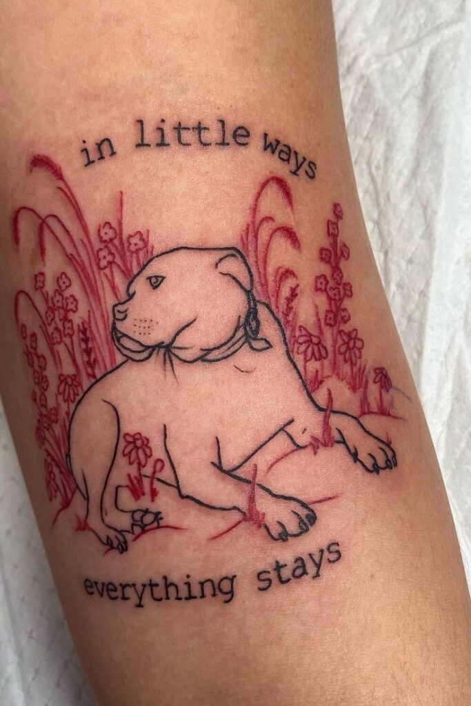 Tattoo of a dog with florals and the phrase in little ways everything stays on skin.