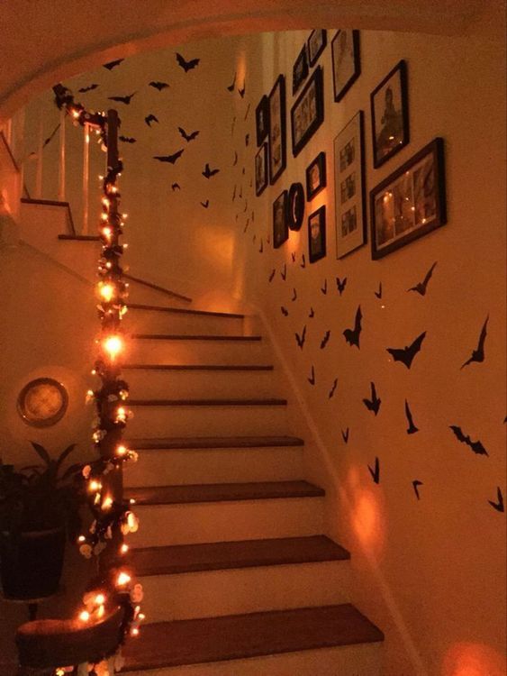 Halloween-decorated staircase with orange lights and bat silhouettes on the wall, creating a spooky atmosphere.