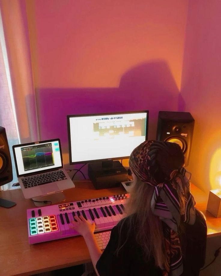 Person creating music with a keyboard controller and laptop in a cozy, softly-lit studio.