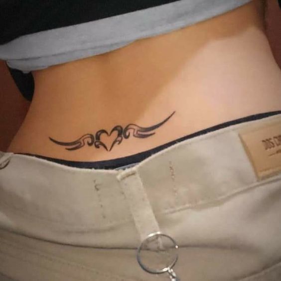 Lower back tattoo with tribal heart design above waistband.