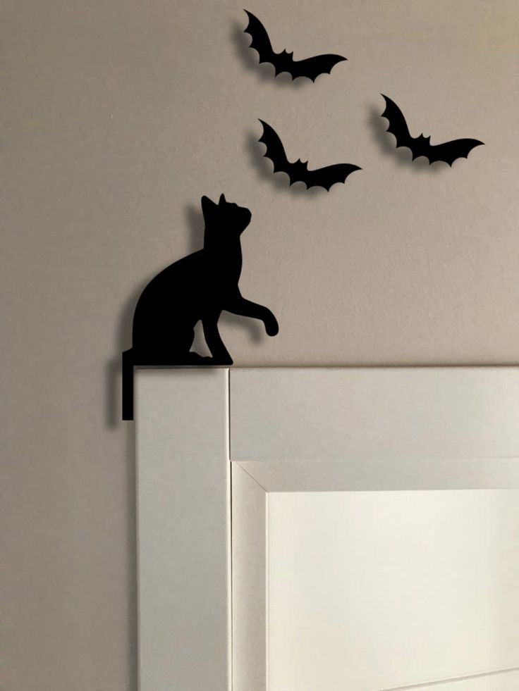 Silhouette of cat and bats as wall decoration on a minimalist white frame.