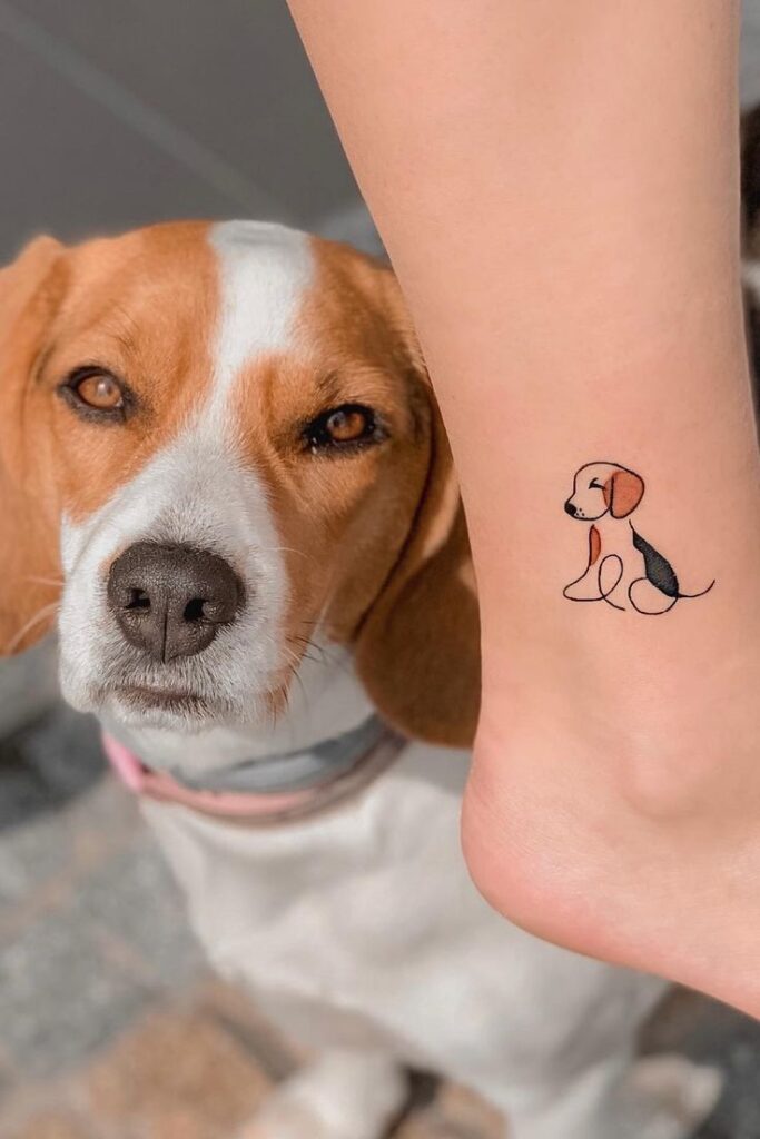 Beagle dog next to a matching minimalist tattoo on a person's ankle, showcasing unique pet art.