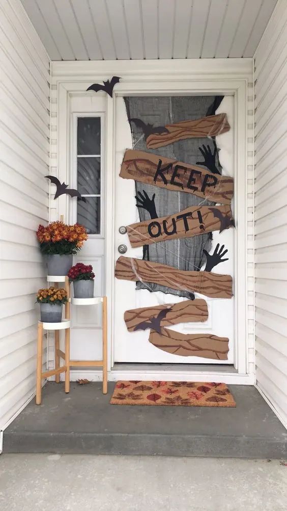 Halloween porch decor with Keep Out sign, bats, and flowers for a spooky welcome.