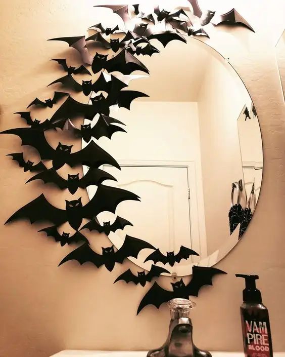 Circular mirror with Halloween bat decorations in a bathroom. Spooky decor with vampire-themed soap.