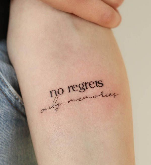 Tattoo on arm reading no regrets, only memories in a mix of fonts, symbolizing a carefree outlook.