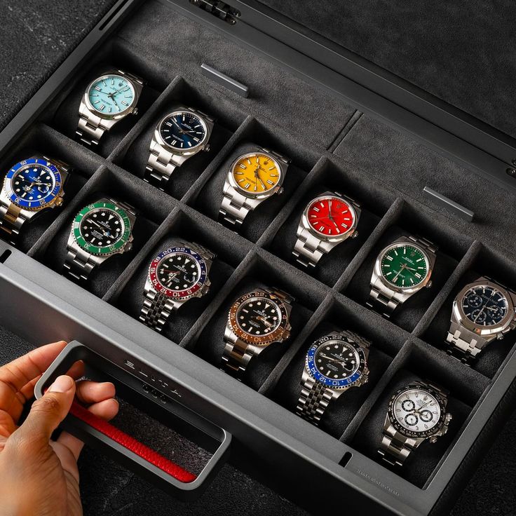 Collection of luxury watches in a display case with various colorful dials and metal bands.