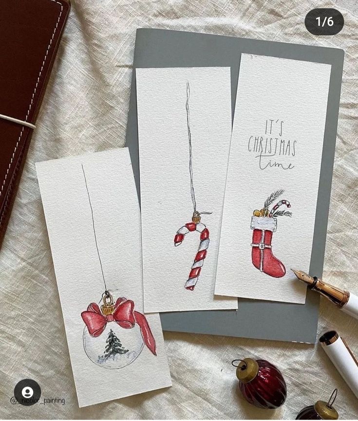 Hand-painted Christmas cards featuring ornaments, candy cane, and stocking on paper. Cozy festive art setup.