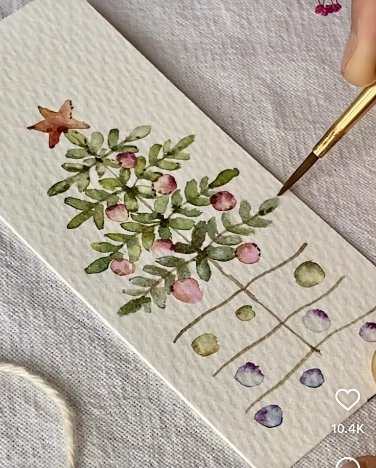 Watercolor painting of a Christmas tree with star, adorned with red and green ornaments, on textured paper.