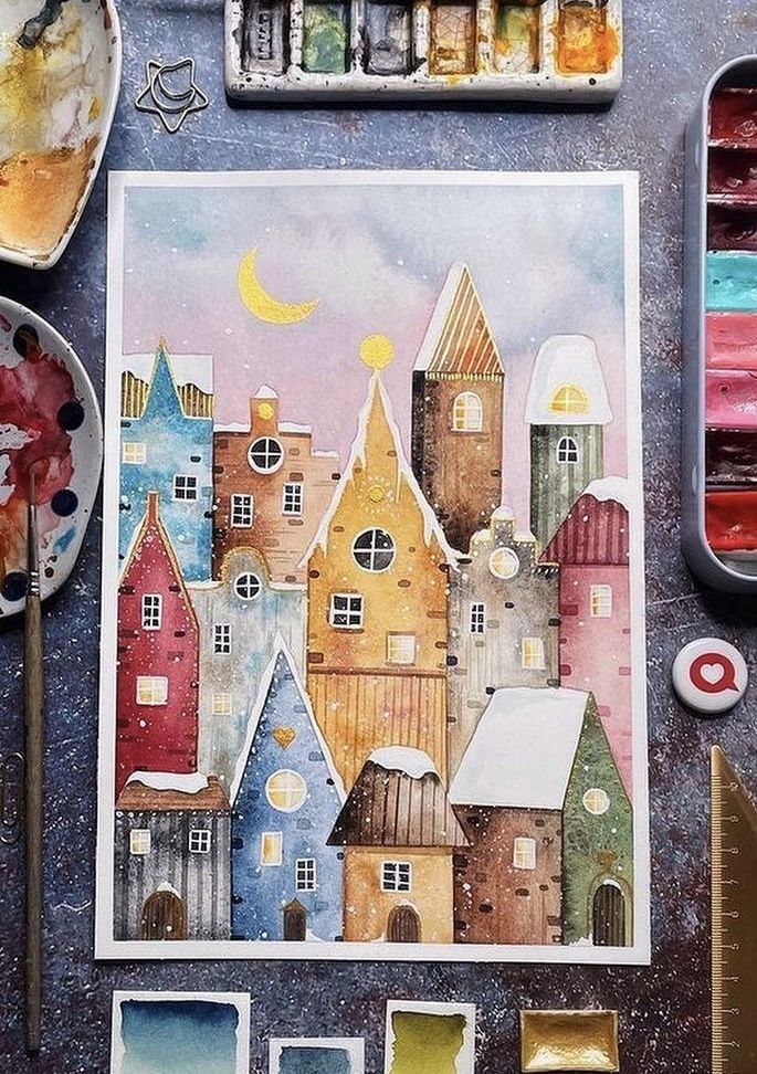 Whimsical watercolor painting of colorful village houses in the snow, surrounded by paint palettes and brushes.