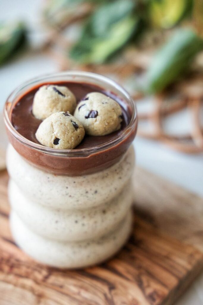 Vegan chocolate smoothie topped with cookie dough balls in a glass jar on a wooden board.