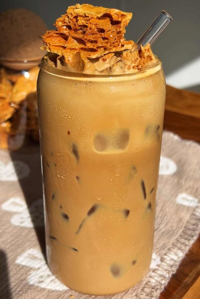 Iced coffee with honeycomb and glass straw on a table, perfect summer refreshment.