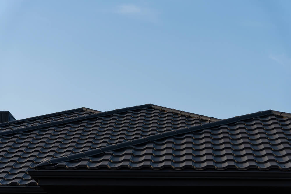 Modern tiled roof against blue sky, featuring durable roofing materials and architectural design.