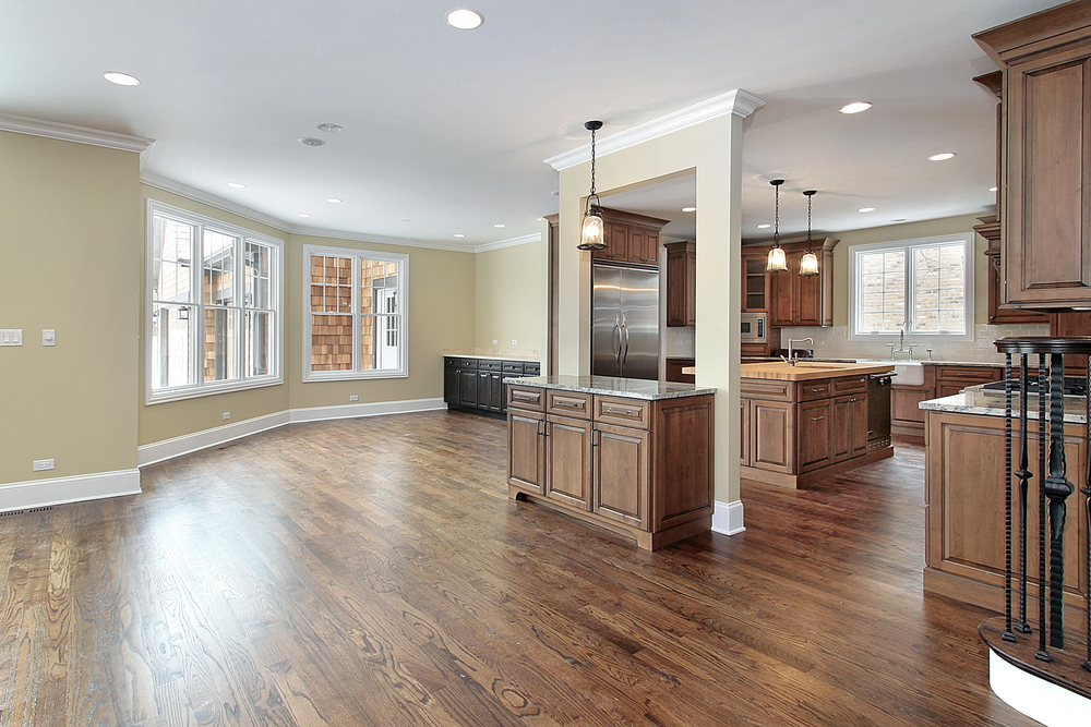 Spacious modern kitchen with hardwood floors, wooden cabinets, and large windows for natural light.