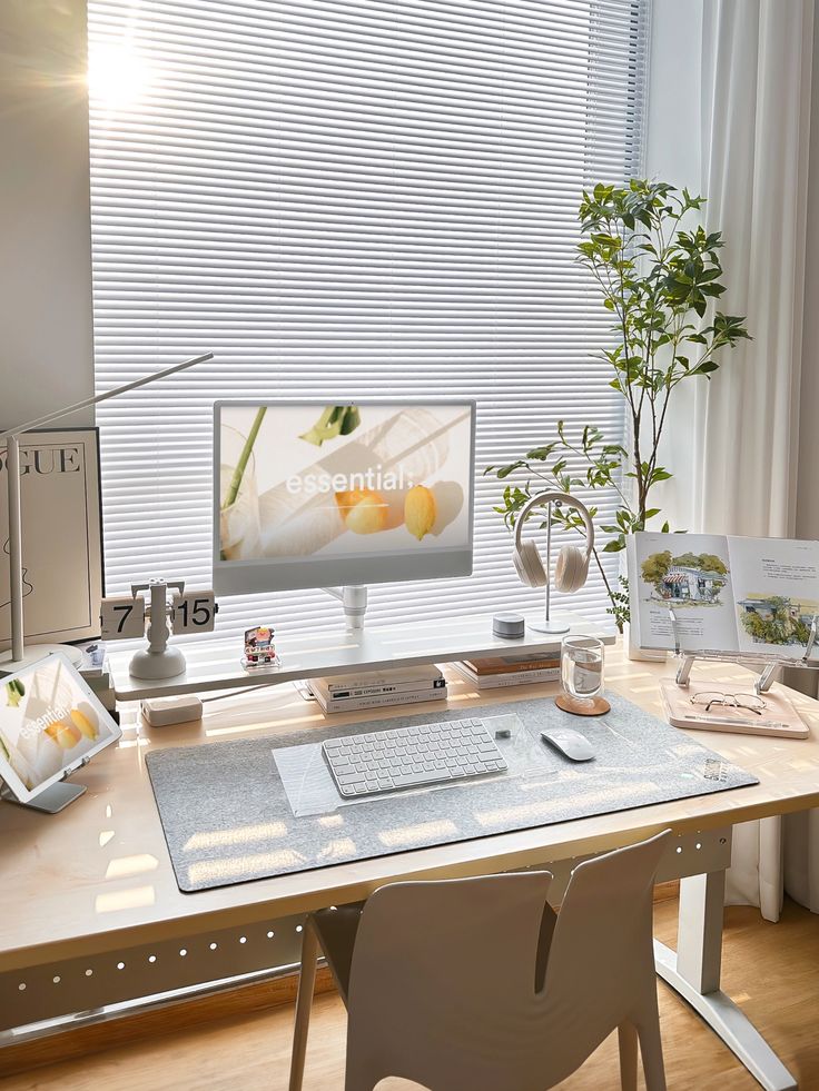 Minimalist home office with computer, plants, and natural light filtering through blinds. Cozy and organized workspace.