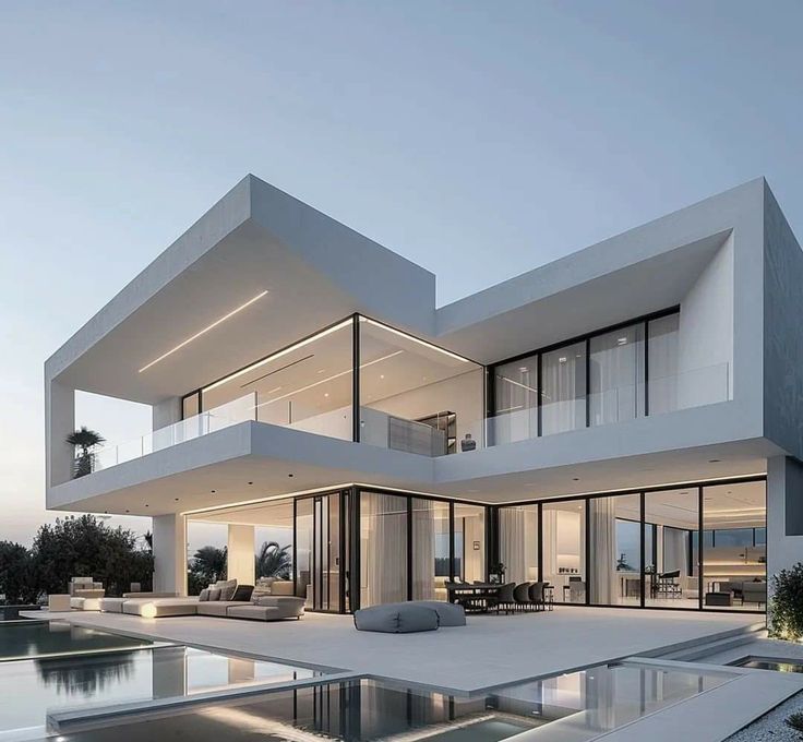 Modern luxury villa with glass walls, spacious patio, and pool at sunset. Minimalist architecture and elegant design.