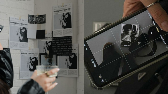 Person photographing a gallery wall with social-themed posters, smartphone camera screen visible in foreground.