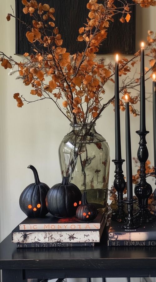 Elegant Halloween decor with black pumpkins, orange foliage, and black candles on a table.