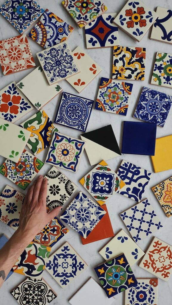 Colorful hand-painted ceramic tiles laid out on a marble surface, featuring intricate traditional designs.