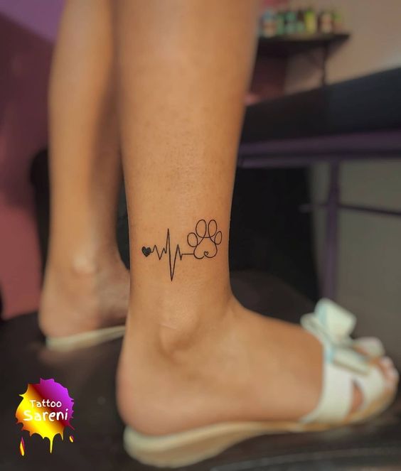 Ankle tattoo featuring heartbeat line, heart, and paw print, symbolizing love for animals and life's rhythm.