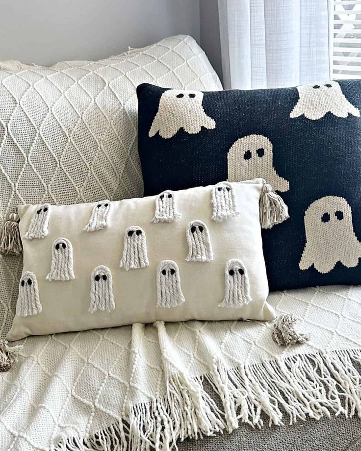 Ghost-themed pillows on a cozy knit blanket, perfect for Halloween decor and adding a spooky touch to home interiors.