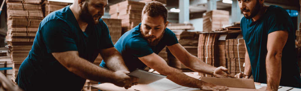 Warehouse workers assembling cardboard boxes with teamwork and focus.