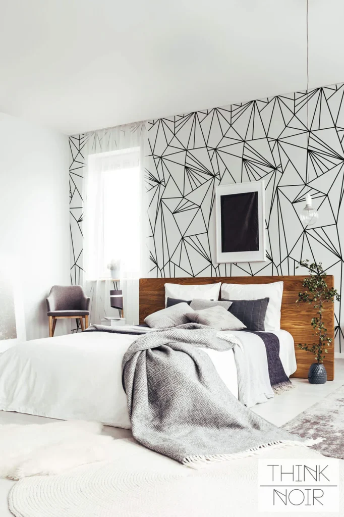 Modern bedroom with geometric wallpaper, cozy bed, and stylish decor.